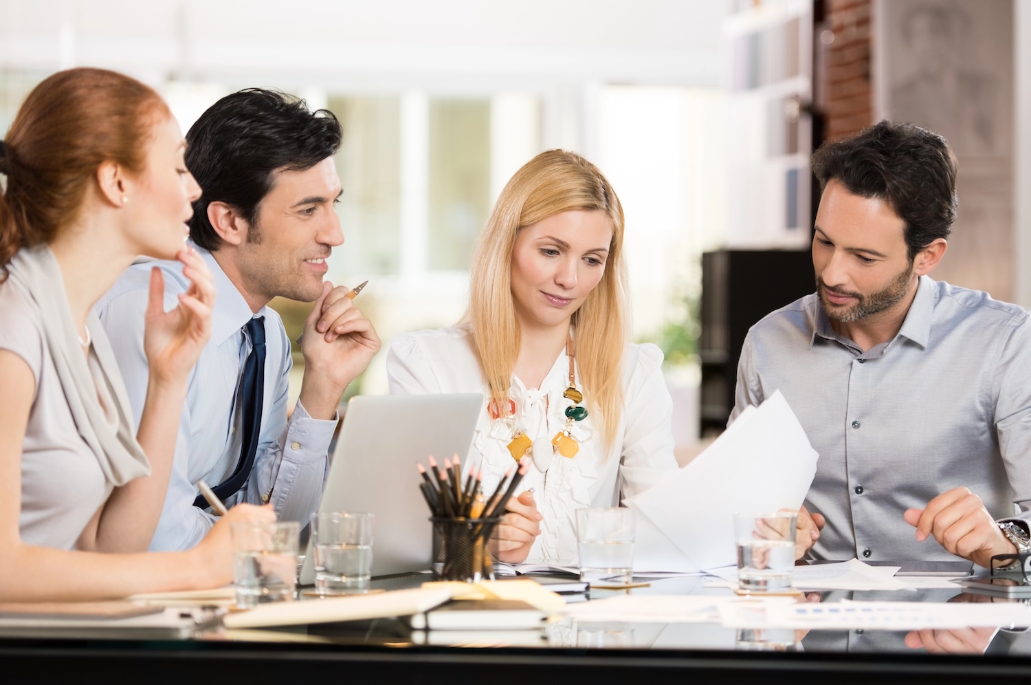 Young veterinarian in a meeting discussing selling his practice. Businessmen and businesswomen discussing the benefits of joint venture. Business teamwork working together in a modern office.